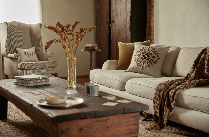 Living room of the Upstate stone house with Coral & Tusk embroidered accent and throw pillows, vintage blanket and flowers on a salvaged wood coffee table