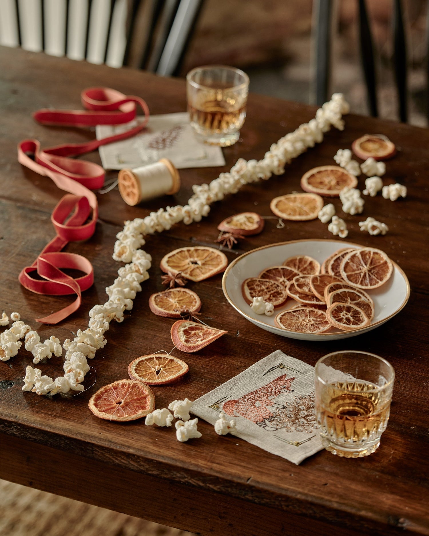 Dried citrus and popcorn garlands next to embroidered Coral & Tusk cocktail napkins on a table
