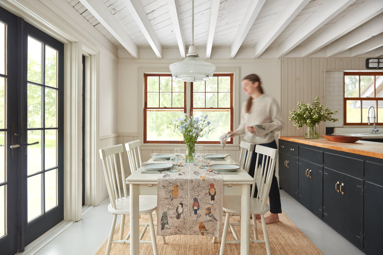Person setting a table with a Coral & Tusk table runner and napkins