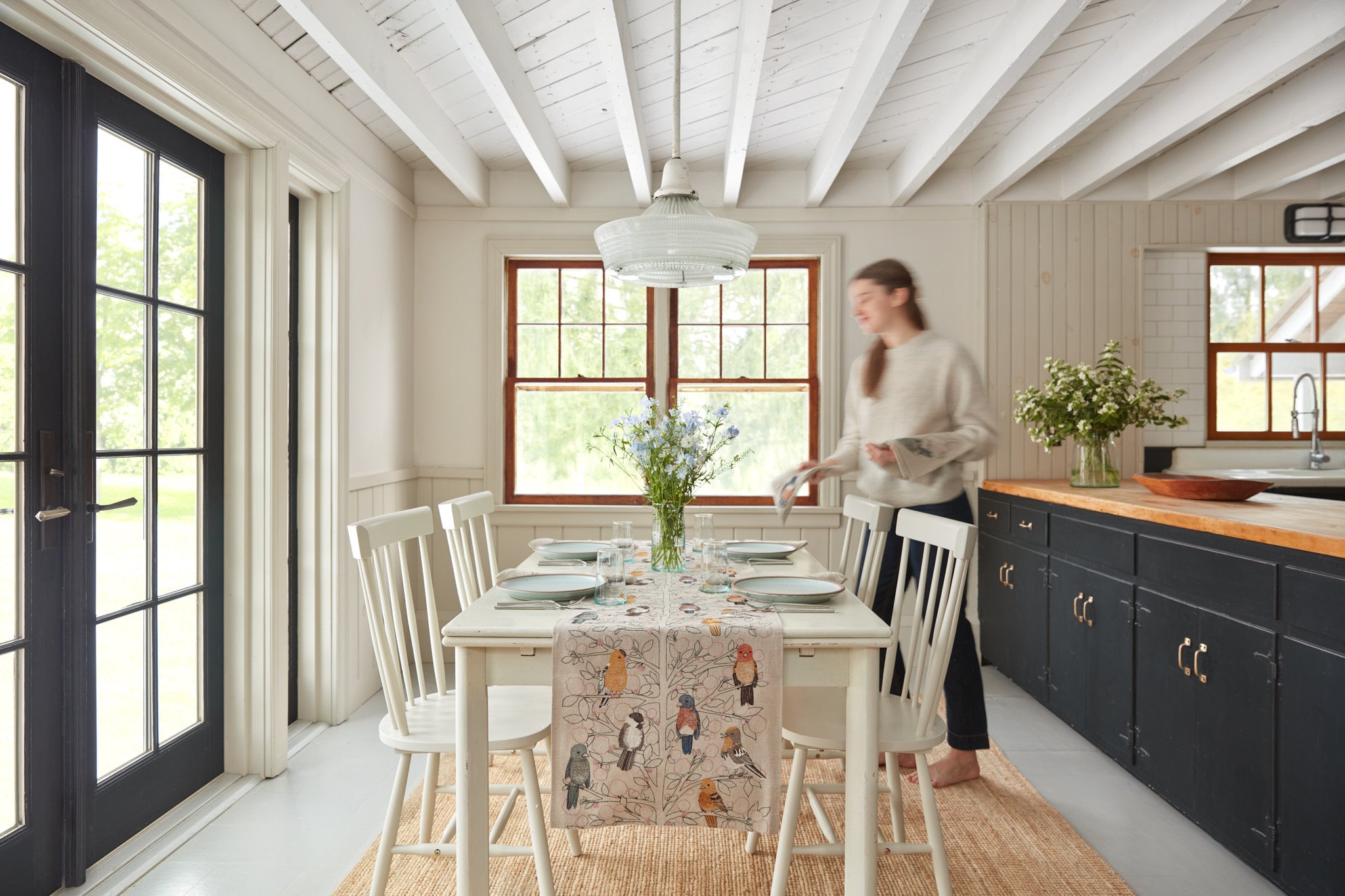 Person setting a table with a Coral & Tusk table runner and napkins