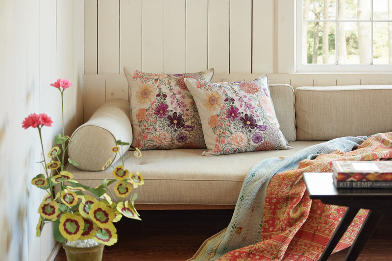 Couch with Coral and Tusk embroidered botanical Paradise Garden Pillows, The Green Vase paper geranium plant, kantha quilt throw and coffee table in front.
