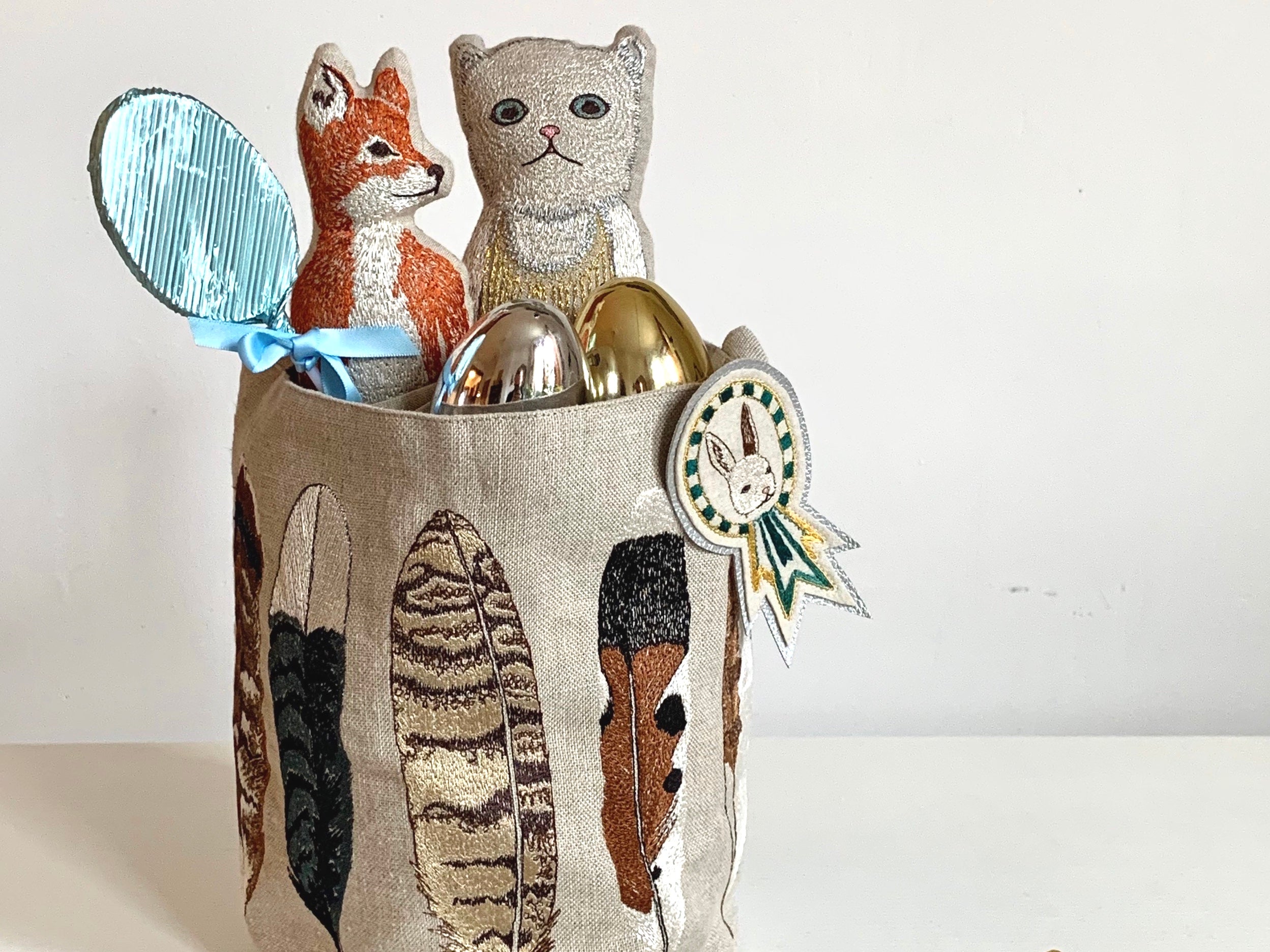 Embrodiered feather bucket holding Easter eggs and pocket dolls