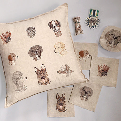 Overhead image of Coral and Tusk Dog themed embroidered products including Dogs Pillow, cocktail napkins, pouch, badge and pal.