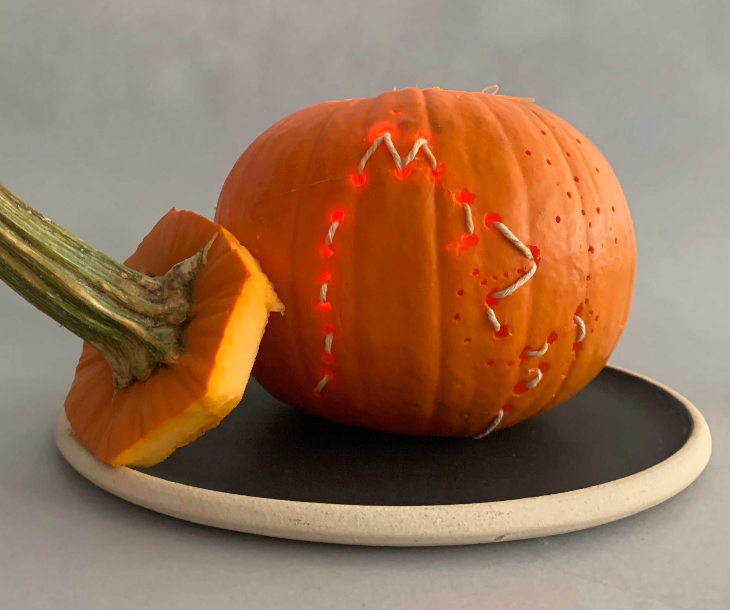 Outline of a fox's profile stitched into a lighted pumpkin for Halloween