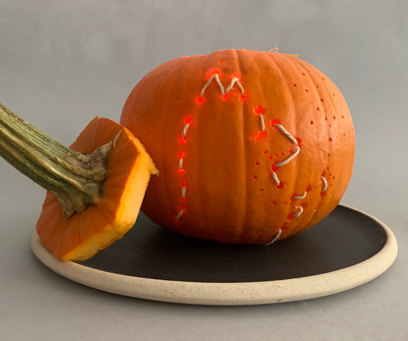 Outline of a fox's profile stitched into a lighted pumpkin for Halloween