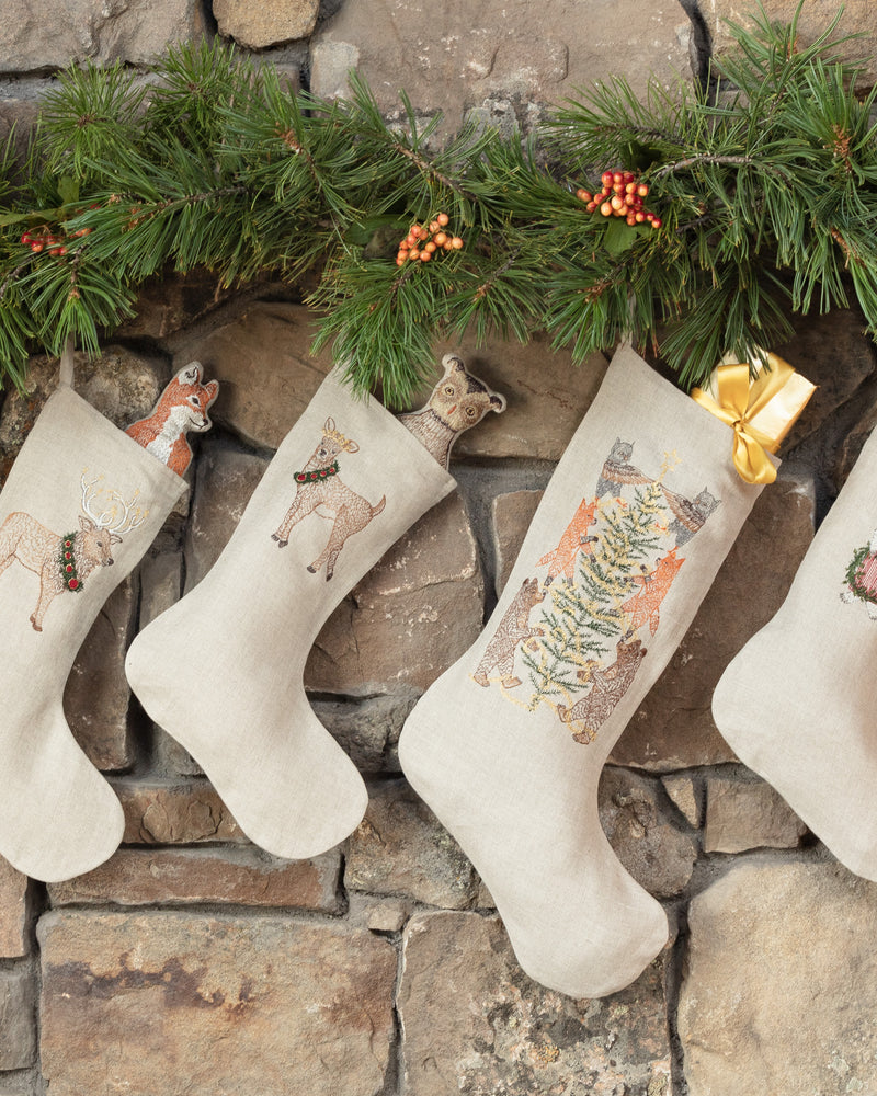 Coral and Tusk embroidered Christmas Stockings hung on a mantle with pine garland.