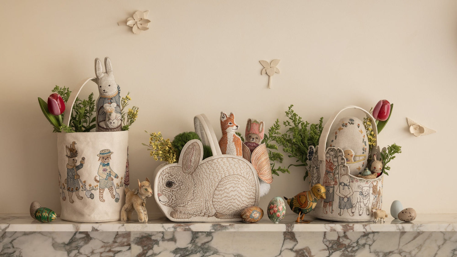 Coral & Tusk Easter Baskets sit on a marble ledge filled with greenery and Easter gifts.