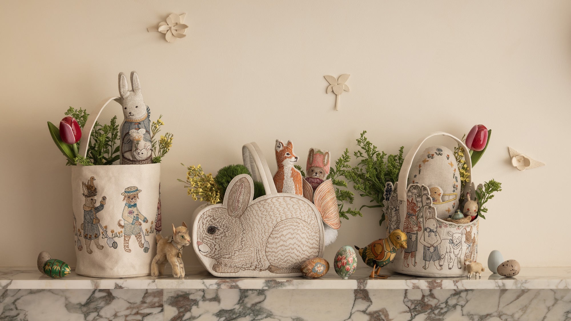 Coral & Tusk Easter Baskets sit on a marble ledge filled with greenery and Easter gifts.