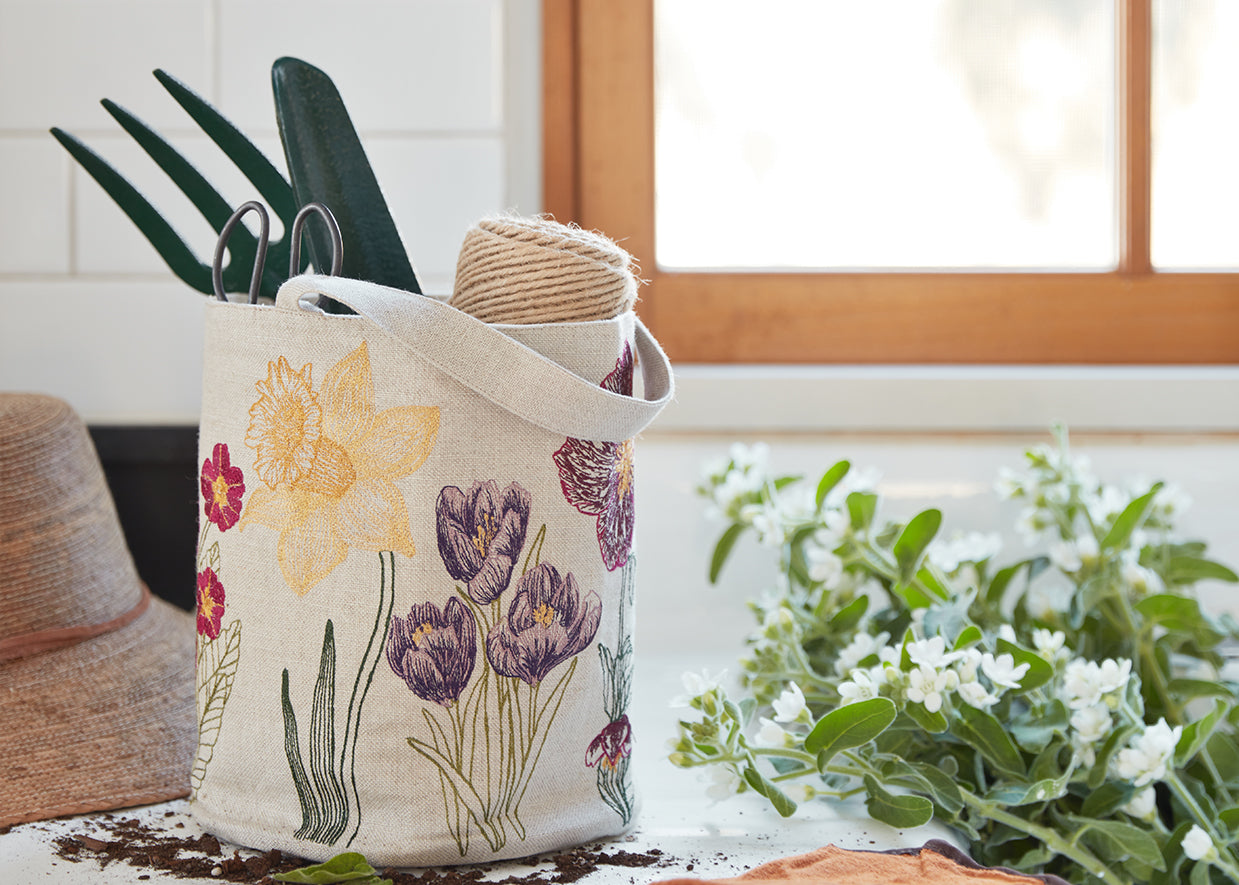 linen canvas bucket embroidered with flowers and holding garden tools