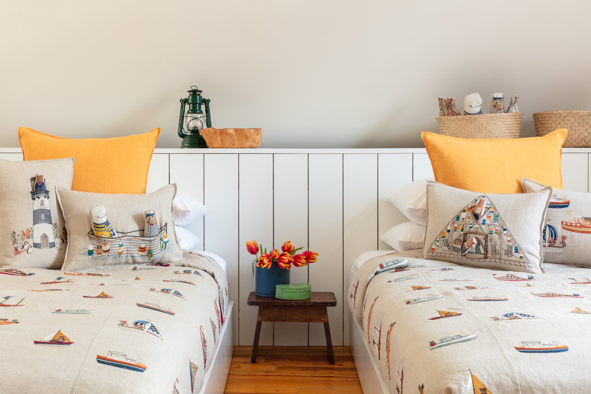 Nautical bedroom interior, two twin beds with yellow accent pillows, Coral and Tusk coastal embroidered pillows and boats fabric duvet.
