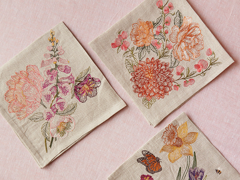 Coral and Tusk embroidered botanical dinner napkins on pink linen table cloth.