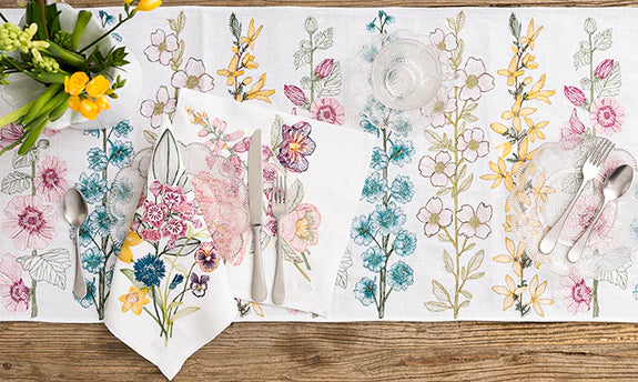 Overhead of dining table set with Coral and Tusk embroidered flower table runner and napkins.