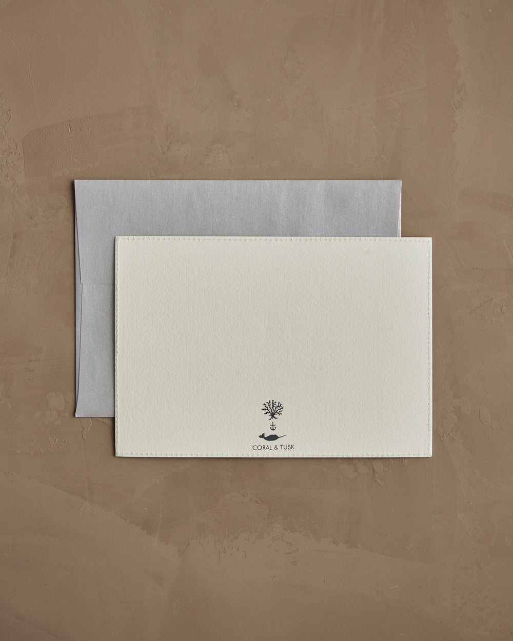 Backside of Coral & Tusk 5 × 7 inch card with a silver envelope.