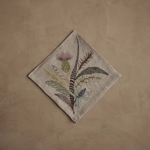 Coral & Tusk 20 × 20-inch folded embroidered linen Thistle Dinner Napkin featuring a bouquet of thistles, greenery, and feathers.