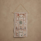 Coral & Tusk embroidered Holiday House Advent Calendar featuring an illustrated brick building facade with 12 hidden pockets, windows showing foxes, bunnies, and bears, and decorative holiday details.