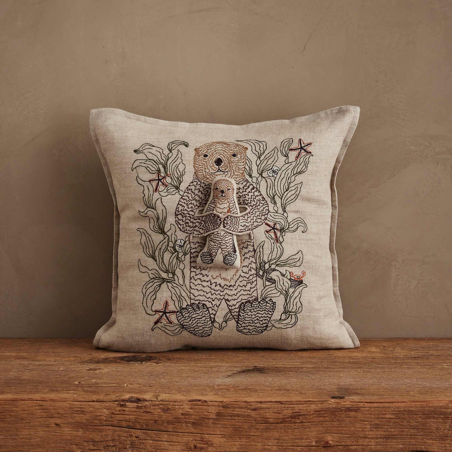Coral & Tusk Otter Mama Pocket Pillow, 12x12 inch natural linen pillow with intricate embroidery of a mama otter cradling a removable baby otter pal among kelp and starfish.