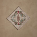 Coral & Tusk embroidered linen Pinecone Garland Dinner Napkin, folded, featuring a pinecone framed by pine sprigs, red berries, and snowberries.