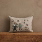 Coral & Tusk Ski Slope Pillow, 12 × 16-inch embroidered linen, showing two bears in winter sweaters and ski outfits standing among pine trees, with rabbits and foxes riding a ski lift and skiing down snowy slopes.