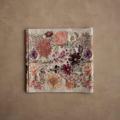 Coral & Tusk linen Paradise Garden Table Runner, folded, featuring detailed embroidery of fine vines and stitched stems with large-scale flowers in full bloom, including sweet peas, sunflowers, roses, dahlias, foxgloves, cosmos, lilacs, poppies, hellebores, and peonies.