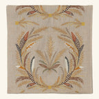 The Coral & Tusk Seconds Sale Wheat Harvest Table Runner, 91″ features an intricate embroidered pattern of wheat stalks and patterned feathers in shades of gold, brown, orange, and cream arranged in symmetrical botanical clusters against a neutral linen background.