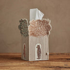 This view of the embroidered Coral & Tusk Treehouse Tissue Box Cover features a fox with a tulip poplar tree and bear with a Gingko tree. The Gingko leaves are a golden reddish brown and the brown bear stands below the tree in the outline of the treehouse's door. The tissue cover is shown on a wooden surface with neutral background.