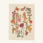 The Coral & Tusk Seconds Sale Secret Garden Card is an off-white handmade paper card featuring an embroidered design of a bear, fox, rabbit, puppy, and chick surrounded by vibrant flowers, mushrooms, a butterfly, and a dragonfly in a whimsical garden scene of embroidered cotton.