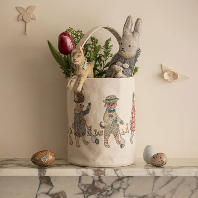 Coral & Tusk Egg Roll Easter bag with embroidered animal illustrations on a marble surface, styled with Easter Bunny Pocket Doll, toys, and eggs.